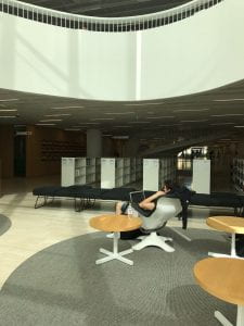 A student sat on a lounge chair inside the library