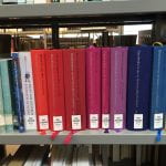 A rainbow-coloured row of books in dutch