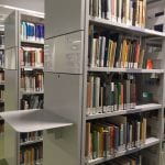 A double-sided freestanding bookshelf with a pull-down shelf for browsing