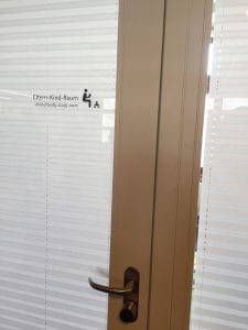 A glass door shielded by a blind with the words 'parent-child room' on it in English and German