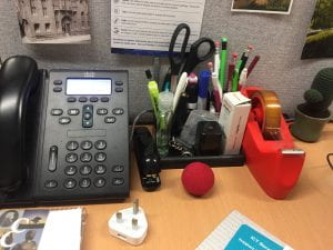 A picture of a telephone headset and stationary caddy with a red nose next to it.